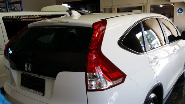 car window tint installation on a white colour Honda CR-V automobile rear view