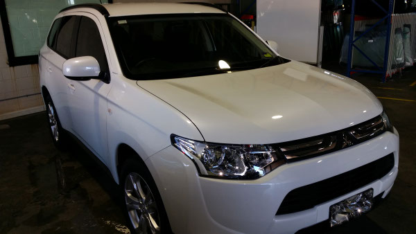 front view white colour Mitsubishi Outlander SUV with perfectly tinted windows